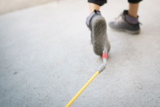 Worker with spray the cleaning sanitize chemical to disinfect COVID-19 virus pathogen on shoes.