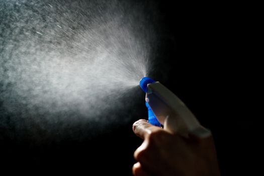 Woman's hands with blue foggy spraying disinfectant to stop spreading coronavirus or COVID-19.