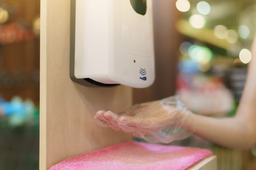 Hands under the automatic alcohol dispenser to avoid the spread of coronavirus.