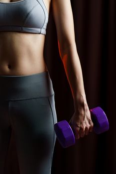 Close up Young woman in gray sportswear exercise at home, doing lifting dumbbells, in quarantine during Coronavirus pandemic.