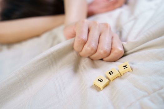 Woman hand sign orgasm on bed with scrabble board showing words sex.