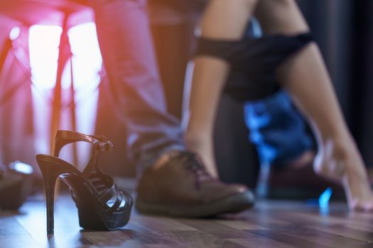 Body part. Couple feel romantic in bedroom, woman sit on his lap and take off panties, black heels shoes on the floor. Sex concept.