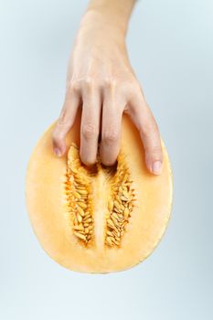 vagina symbol, hand with melon on white background. Concept masturbation