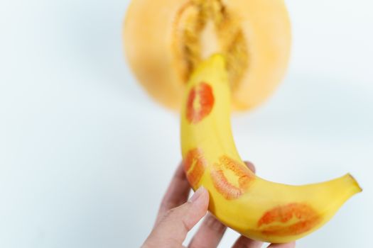 Melon and banana with red lipstick marks on white background, Sex concept.