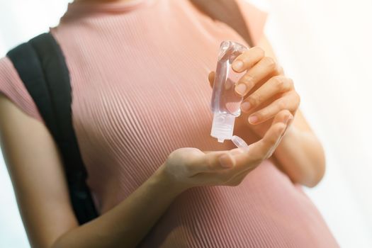 Coronavirus concept : woman using sanitizer gel when backpack traveling at airport or train station.