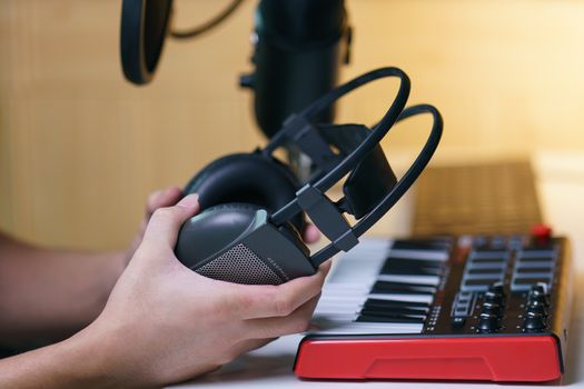 Hand holding earphone near sound mixing console board. Equipment for the music studio.