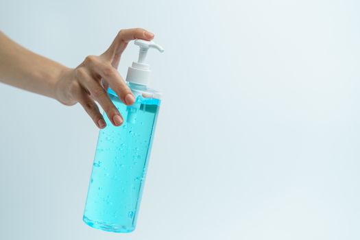 Hand with hand sanitizer in a clear pump bottle on a white background.