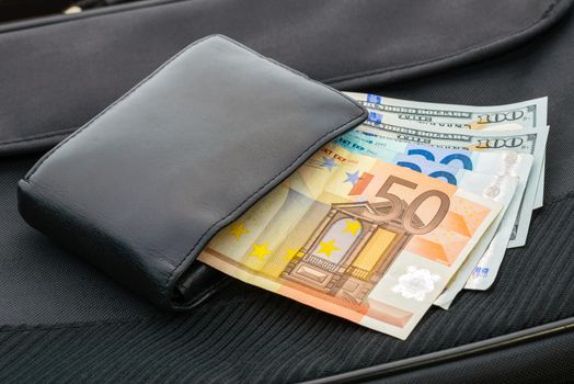 A black leather wallet with Euro and Dollar banknotes