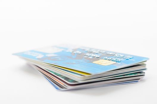 A pile of several colored credit cards, stacked on white background