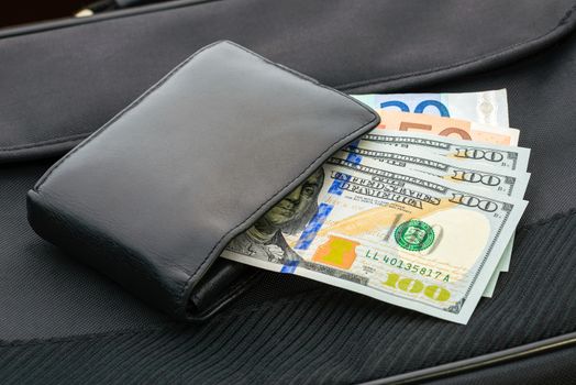 A black leather wallet with Dollar  and Euro banknotes