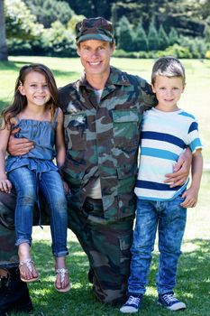 Happy soldier reunited with his son and daughter in the park on a sunny day