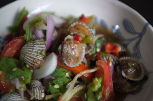 CLOSE UP view , Cockles salad / Hot and spicy shellfish blood cockles salad mix vegetable tomato herb and spices , thai style food