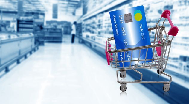 Shopping trolley and  credit card on super market blur background, online payment, electronic commerce financial concept  