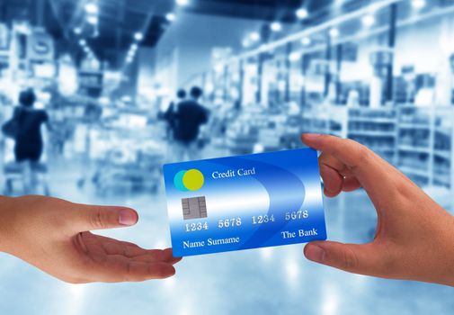 Hand holding credit card on super market blur background, online payment, electronic commerce financial concept  
