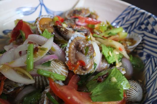 CLOSE UP view , Cockles salad / Hot and spicy shellfish blood cockles salad mix vegetable tomato herb and spices , thai style food