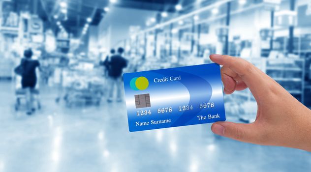 Hand holding credit card on super market blur background, online payment, electronic commerce financial concept  