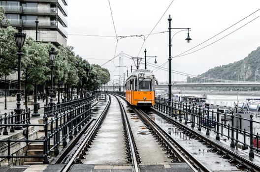 Number 2 orange tram passes along the Danube River from Erzhebet Bridge near Belgrade Embankment. Budapest, Hungary