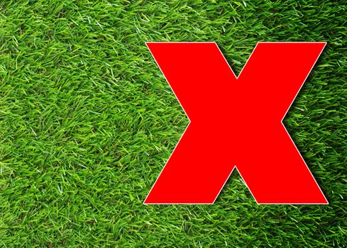 Red cross on green grass background, wrong concept