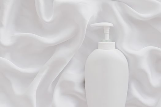 Blank label cosmetic container bottle as product mockup on white silk background, hygiene and healthcare