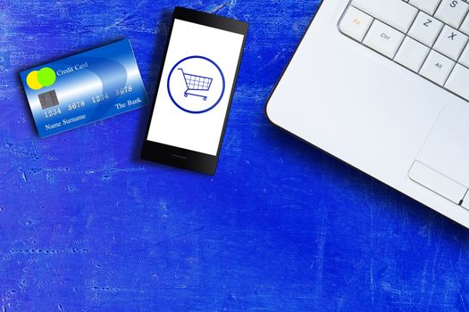 Online shopping concept, mobile phone, credit card and laptop on blue vintage background with copy space