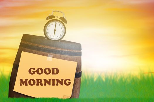 Good morning and wake up concept, alarm clock and wood barrel on green grass