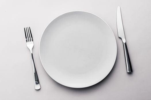 Empty plate and cutlery as mockup set on white background, top tableware for chef table decor and menu branding design