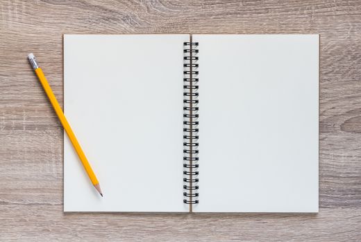 Blank notebook and yellow pencil on wooden table