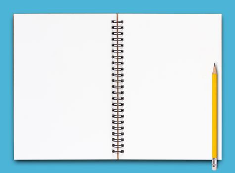 Open notebook and yellow pencil on blue background