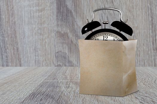 Time management concept, business planning, shopping paper bag and alarm clock on wood background 