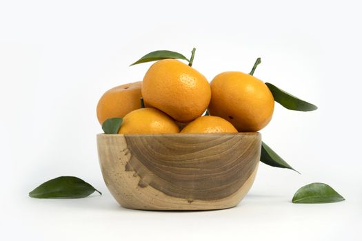 Citrus sinensis ( called jeruk baby santang ) with leaves – local fresh fruit from Indonesia, on a wooden basket / bowl Isolated on white background