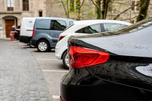 Row of at street side parked cars. View to the rear of cars - image