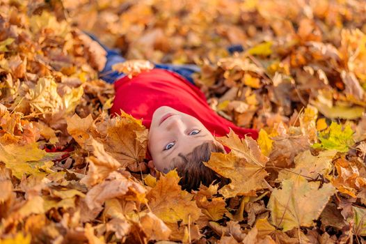 close portrait of handsome young guy in autumn yellow foliage