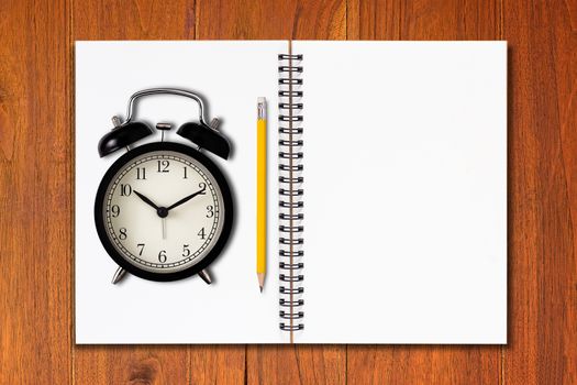 Time management concept, business planning, open notebook and alarm clock on wood table