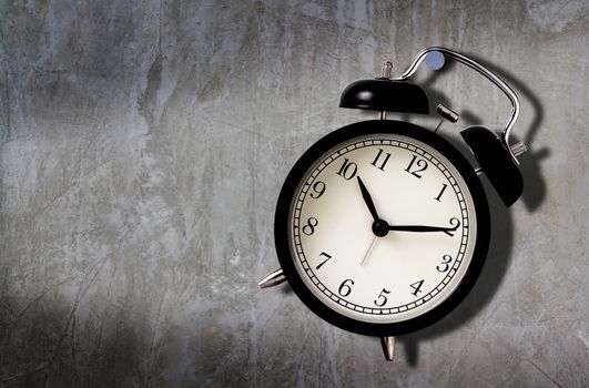 Time management concept, business planning, patience under pressure, alarm clock hang on the concrete wall 