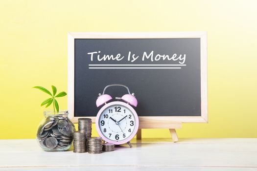 A concept about the relationship between time and money. An alarm clock and stack of coins.

