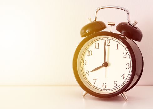 Black retro alarm clock on white table, sunrise time, morning concept 