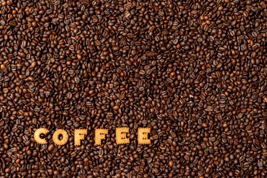 The word COFFEE  made from biscuit letters on a dark coffee bean background - image