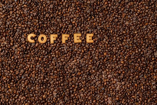 The word COFFEE  made from biscuit letters on a dark coffee bean background - image