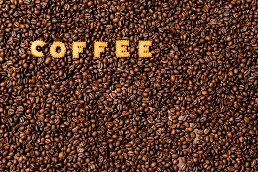 The word COFFEE  made from biscuit letters on a dark coffee bean background - image