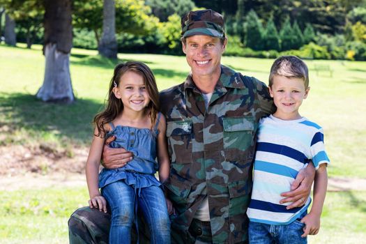 Happy soldier reunited with his son and daughter in the park on a sunny day