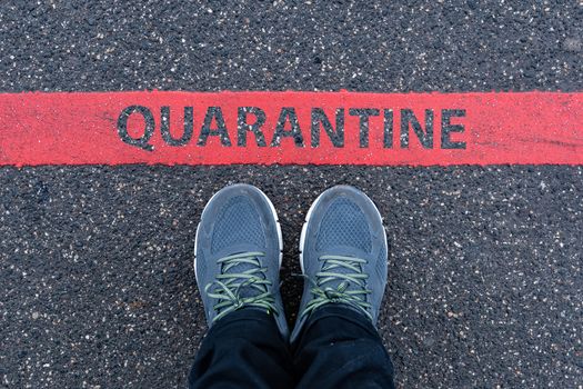 man in sneakers standing next to a red line with text QUARANTINE, restriction or safety warning concept