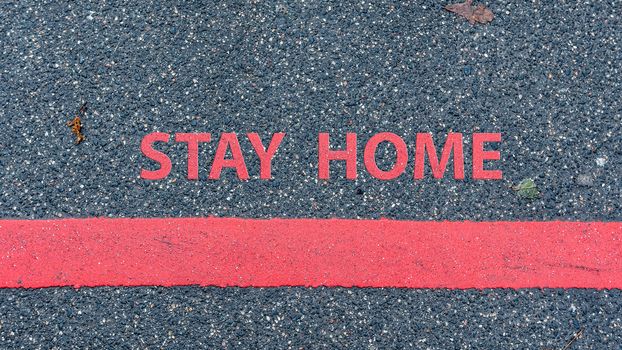 top View of the asphalt road with red line and text STAY HOME, restriction or safety warning concept