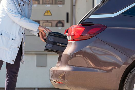 woman loading suitcase into car trunk, preparation for trip