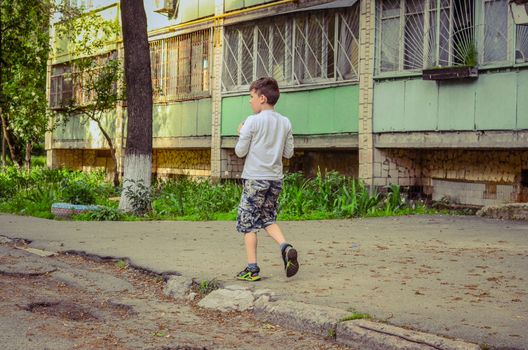 Little boy walks near his old house