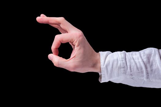Human hand in a white shirt shows the OK or ring gesture sign on isolated black background