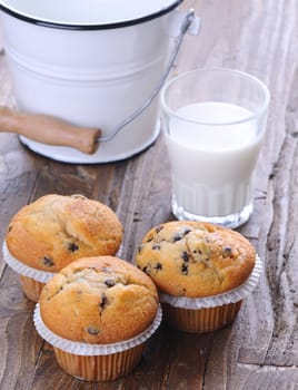 Cupcakes with glass of milk on wooden table.