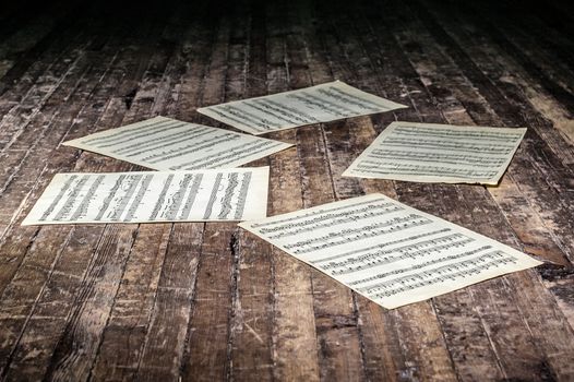 music sheets with notes of a musical work lie on the old floor in the dark