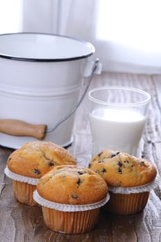 Cupcakes with glass of milk on wooden table.