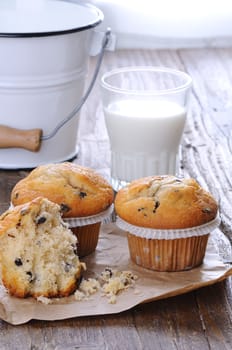 Cupcakes with glass of milk on wooden table.