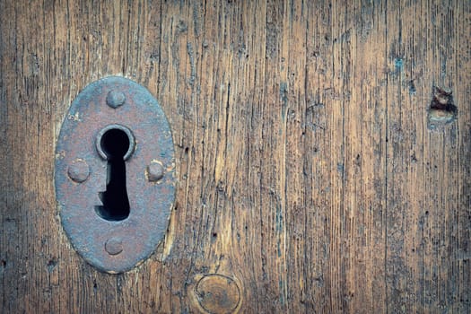 Close-up of old weathered door with rustic keyhole.
